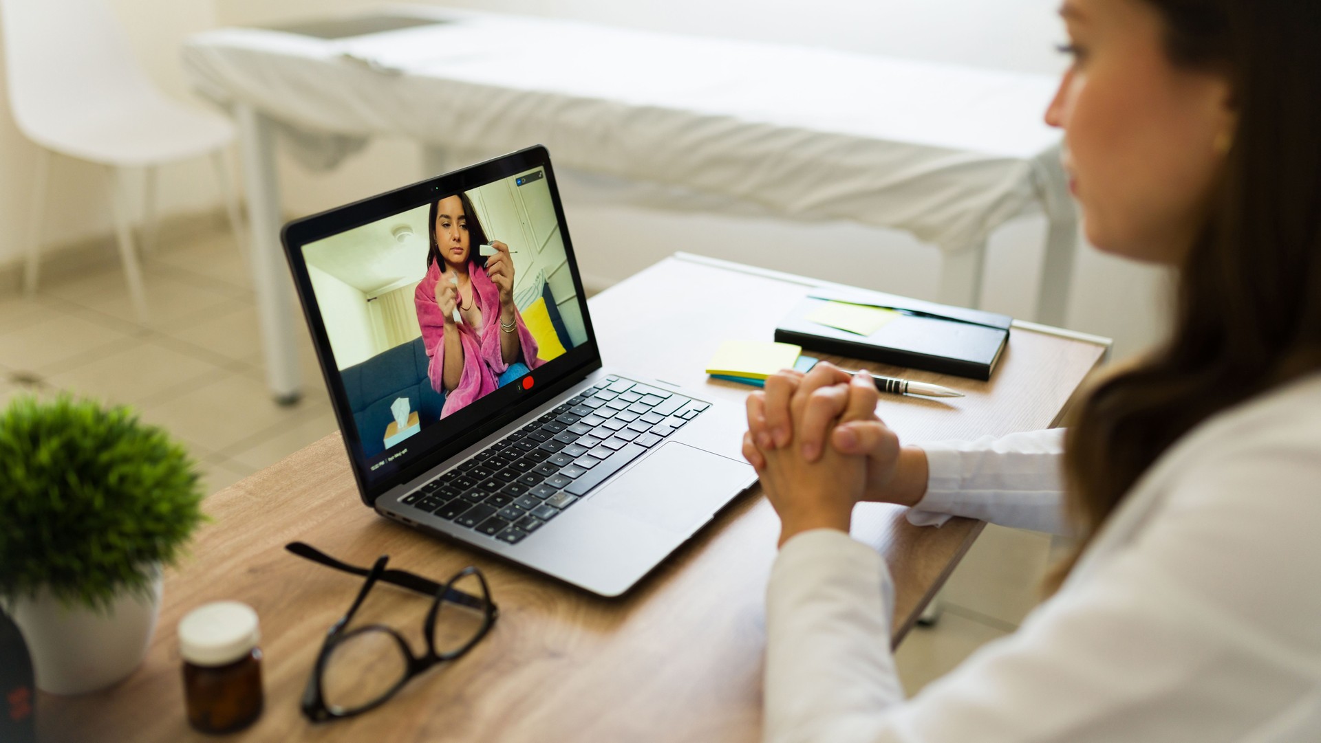 Female doctor listening to her patient during a video call consultation showing a thermometer to the camera