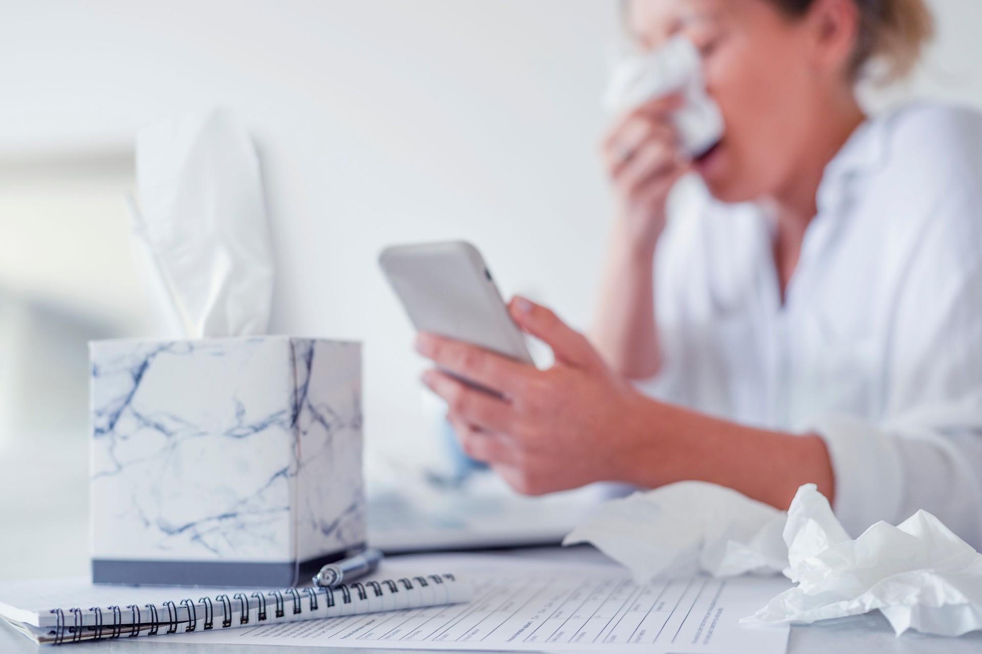 Woman with cold, flu or allergies using a mobile phone.