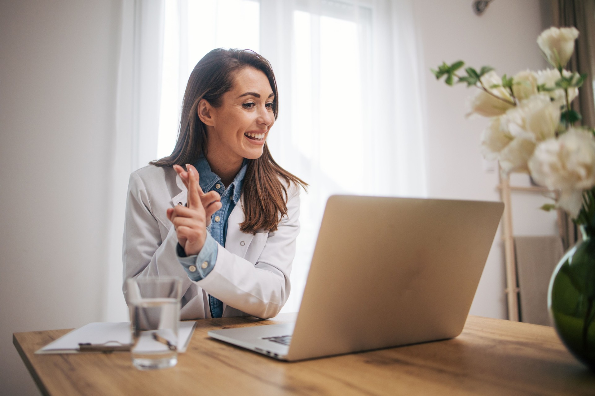 Female doctor sitting in home office and using laptop computer.